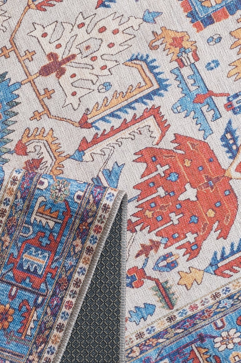 A close-up of the Yonder Blue Cream Washable Rug (LCC3045) shows its red, blue, orange, and cream patterns. One corner folds to reveal a dark non-slip backing—ideal for high-traffic spaces and easy care as a washable rug.