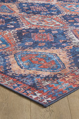 A close-up of the Zephyro Kilim-Design Washable Rug (LCC3008), featuring intricate geometric and floral patterns in blue, red, orange, and cream on a wooden floor—ideal for high-traffic areas.