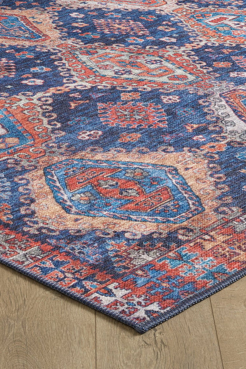 Load image 1 in gallery view. A close-up of the Zephyro Kilim-Design Washable Rug (LCC3008), featuring intricate geometric and floral patterns in blue, red, orange, and cream on a wooden floor—ideal for high-traffic areas.