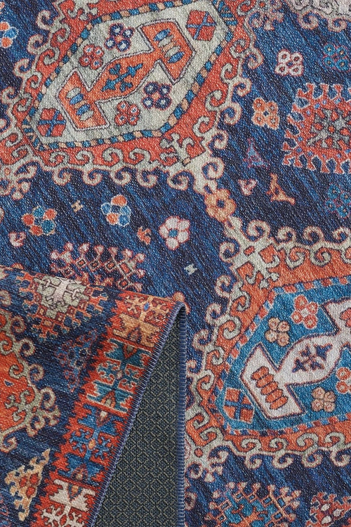 Load image 1 in gallery view. Close-up of the Zephyro Kilim-Design Washable Rug - LCC3008, featuring intricate geometric and floral patterns in blue, red, and cream. A folded corner reveals its detailed underside—perfect for high-traffic areas.