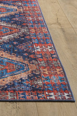 A corner of the Zephyro Kilim-Design Washable Rug - LCC3008 (Custom Size), featuring vibrant red, blue, and white geometric patterns, rests on a light wood floor—ideal for high-traffic and allergy-sensitive homes.