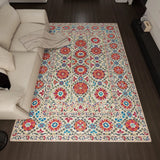 Decorative rug with floral pattern on a wooden floor next to a beige sofa.