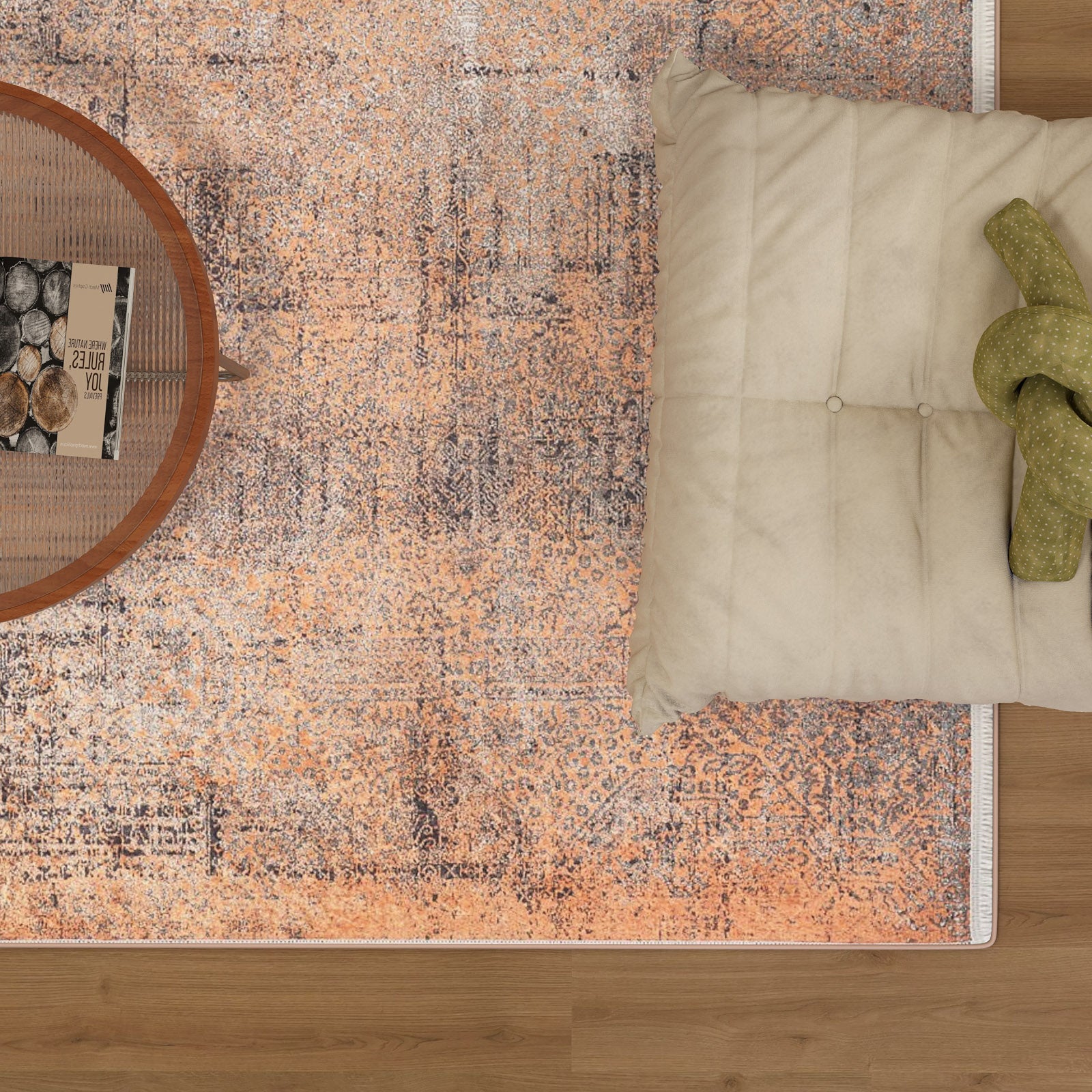 The Modern Mosaic - Machine-Washable Rug JR1846, in a vibrant orange pattern and perfect for high-traffic areas, rests on a wooden floor under a round coffee table with books and a bowl, accented by a cream cushion with a green knitted accessory.