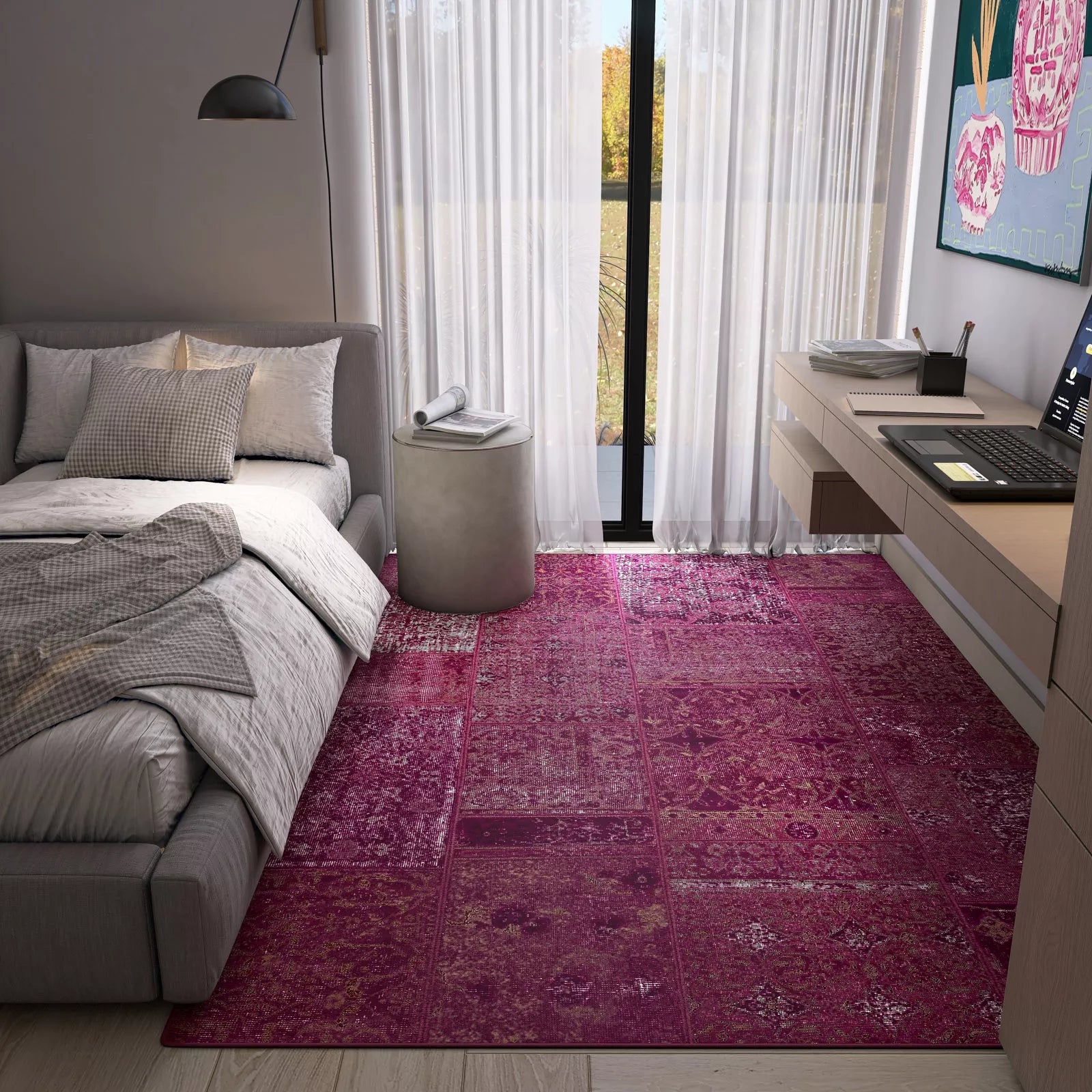 Modern bedroom with a pink rug, gray sofa, and desk.