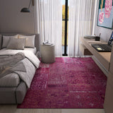 Modern bedroom with a pink rug, gray sofa, and desk.