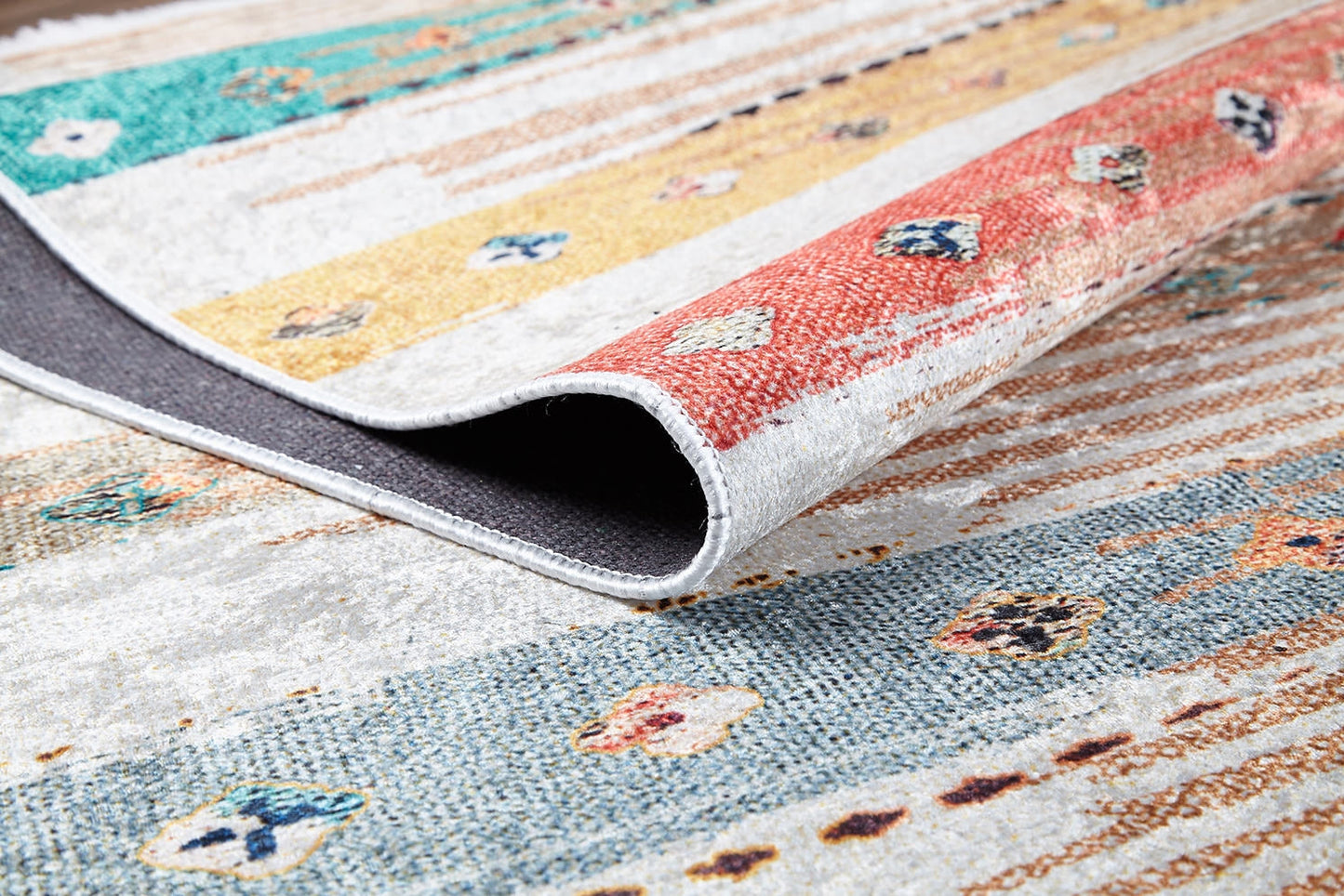 A close-up of the Nomad's Nostalgia - Washable Rug - JR1669 (Custom Size) featuring red, yellow, and teal stripes with geometric patterns; partially folded to reveal its texture—ideal for high-traffic areas.
