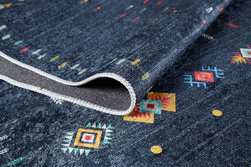 Load image 1 in gallery view. A close-up of the Wanderer's Way - Washable Rug - JR5101 (Custom Size) in dark blue, featuring colorful geometric and tribal patterns, a folded corner showing the back and white stitched edging—ideal for high-traffic areas.