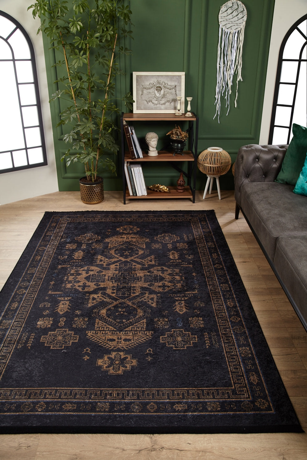 A living room with the Ancient Legacy - Washable Rug - JR1890, ideal for high-traffic spaces, a gray tufted sofa with green pillows, a potted plant, small bookshelf with decor accents, and green paneled walls featuring arched windows and a wall hanging.
