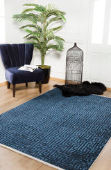 A modern room with the Art Deco Elegance - Washable Rug - JR1224 (blue patterned, easy to clean—perfect for high-traffic areas), a navy velvet chair with books, a potted plant, an empty birdcage, and a black fur rug on light wood flooring.