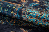 Close-up of the Blossoming Bazaar - Washable Rug (JR1862): a rolled-up, dark-colored rug featuring intricate blue, teal, and yellow floral patterns on black. Its visible texture and durable weave make it ideal for high-traffic areas.