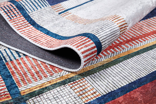Bild 1 in Galerieansicht laden. A close-up of the Bohemian Nightscape - Washable Rug (JR1701), featuring red, blue, gold, and white geometric patterns. Partially folded to highlight its texture and intricate details—ideal for high-traffic areas.