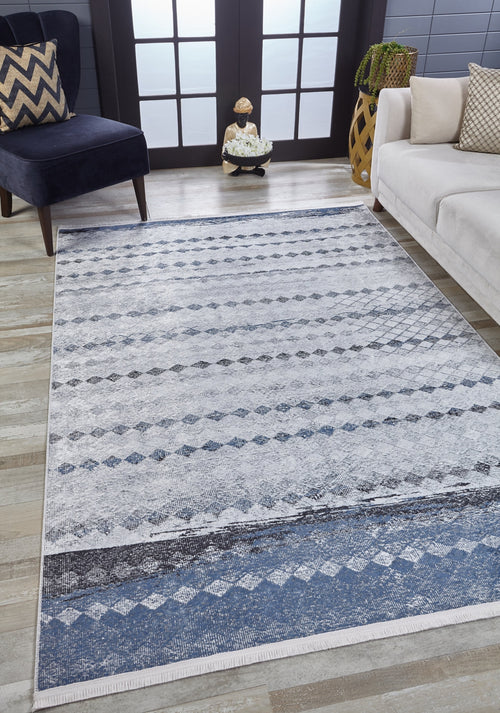 Load image 1 in gallery view. A modern living room features the Bohemian Reverie - Washable Rug - JR1974 (Outlet) US in blue and white on wood floors, paired with a navy chair, chevron pillow, cream sofa, plant stand, and double glass doors for natural light.