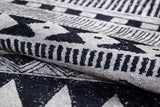Close-up of the Bohemian Sunrise - Washable Rug - JR1713, folded to show its gray-anthracite hue with black and white geometric patterns—ideal for adding bold, durable texture to high-traffic spaces.