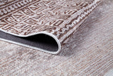 A close-up of the Bohemian Treasure - Washable Rug (JR1586) highlights its geometric brown and beige pattern, with the edge lifted to show the underside—perfect for allergy-sensitive or high-traffic textured areas.