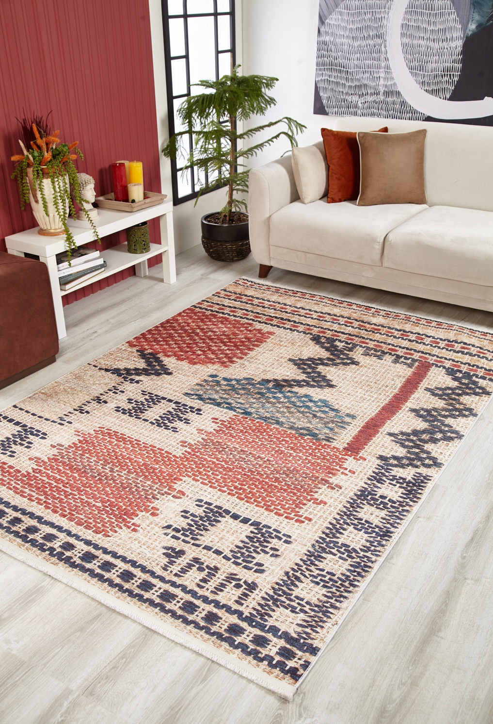 A modern living room with a beige sofa, white coffee table with plants, potted tree, and the Boho Bliss - Washable Rug - JR1723 in red, blue, cream, and beige tones on a light wood floor.