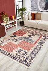 A modern living room with a beige sofa, white coffee table with plants, potted tree, and the Boho Bliss - Washable Rug - JR1723 in red, blue, cream, and beige tones on a light wood floor.