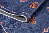 A close-up of the Boho Chic Tapestry - Washable Rug (JR5083), featuring blue, red, and yellow geometric patterns. The allergy-friendly rug is slightly folded to reveal its stitched edge and underside.