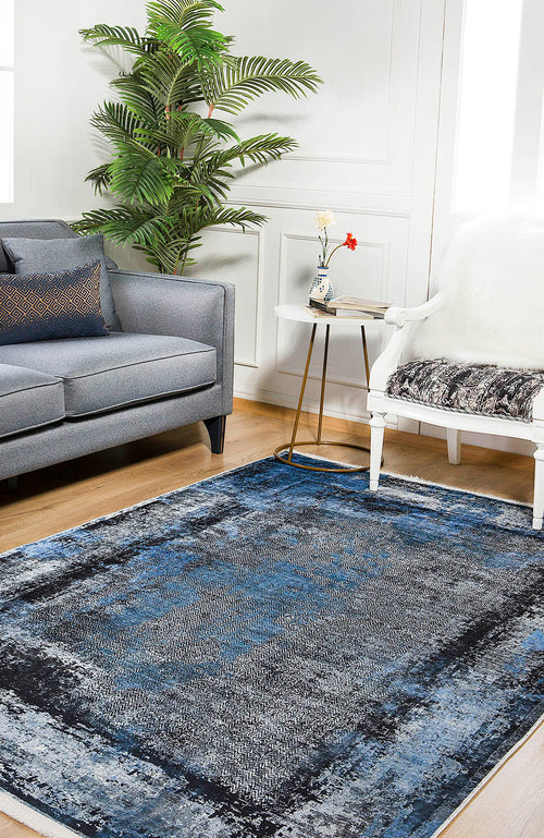 Load image 1 in gallery view. A modern living room features a gray sofa, white chair with a throw, and the Bold and Minimalist - Washable Rug - JR1229, perfect for high-traffic areas. A small side table with flowers and a green potted plant freshen up the white walls.
