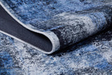 A close-up of the Bold and Minimalist - Washable Rug - JR1229, featuring a textured blue and black pattern with a folded corner displaying the underside—ideal for high-traffic areas.