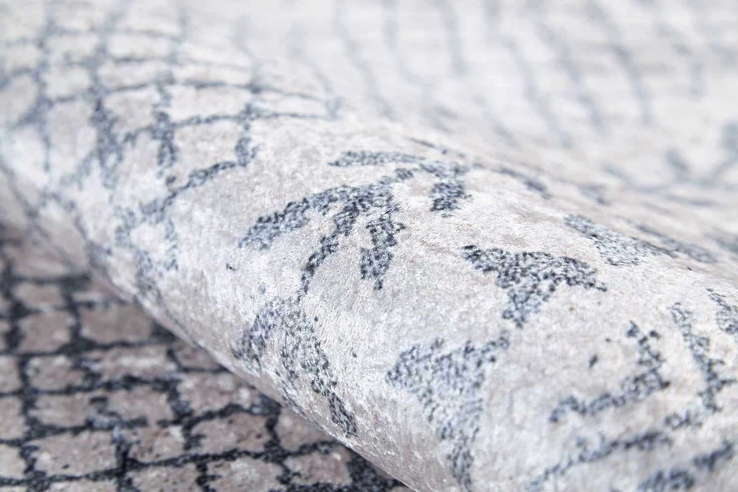 A close-up of the Borderline Brilliance - Washable Rug (JR1987) in light gray-anthracite, featuring a textured, slightly shiny surface with an abstract dark gray pattern—perfect for high-traffic areas and easy to wash.