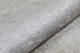 A close-up of Cinnamon Swirl - Washable Rug - JR425 shows its gray, textured, metallic-finish surface—resembling recycled fiber and crafted for high-traffic areas, combining durability with washable convenience.
