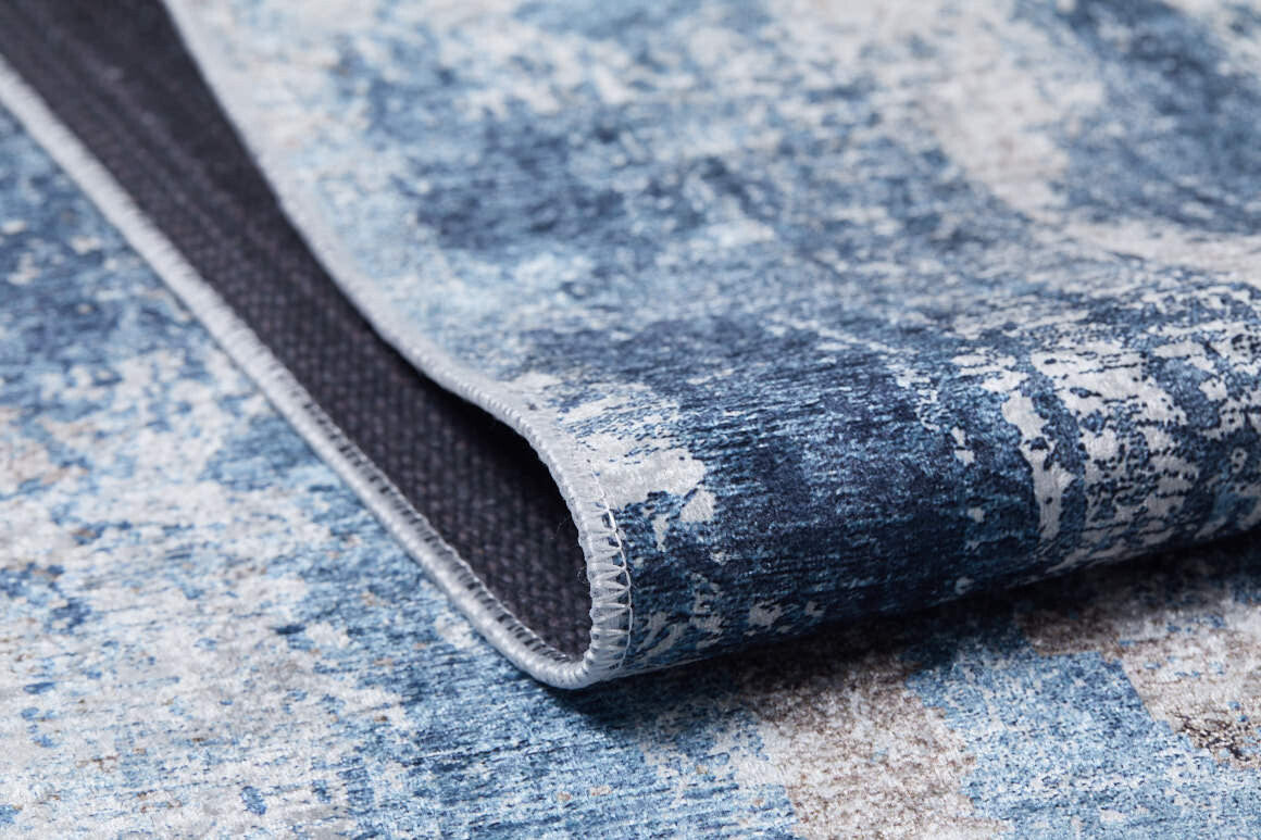 A close-up of the Classic Bordered - Washable Rug - JR1197 in blue and white, with a folded corner revealing its textured underside and stitched edge—ideal for allergy-sensitive homes or busy, high-traffic spaces.