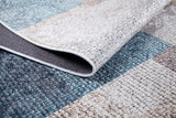 Close-up of the Classic Check - Washable Rug - JR1955 with a folded corner, displaying its blue, gray, and beige patchwork. Perfect for allergy-sensitive homes and high-traffic areas, featuring detailed texture and visible stitching.