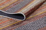 A close-up of the Coastal Breeze - Washable Rug (JR1549) showcases its geometric diamond pattern with colorful stripes. One corner is folded, revealing the allergy-sensitive rug’s underside.
