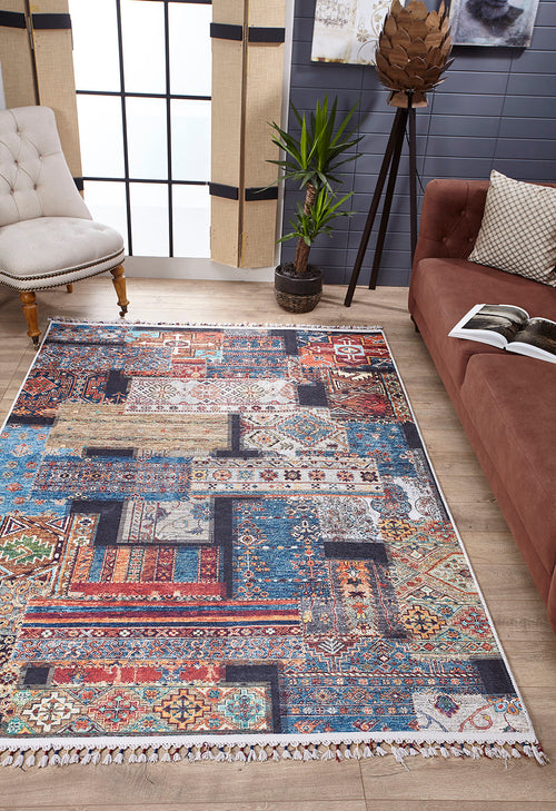 Load image 1 in gallery view. The Colorful Composition - Washable Rug - JR5107, with geometric and floral patterns, brightens a modern living room furnished with a brown sofa, light armchair, potted plant, and large windows draped in beige curtains.