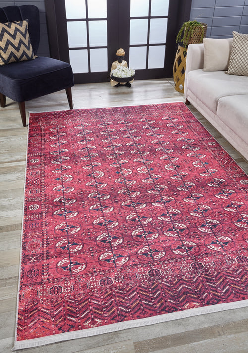 Load image 1 in gallery view. A living room features the Desert Dreamscape - Washable Rug - JR1940 in red patterns on light wood flooring, paired with a dark blue chair, chevron pillow, white sofa, and a vase by a frosted glass window.