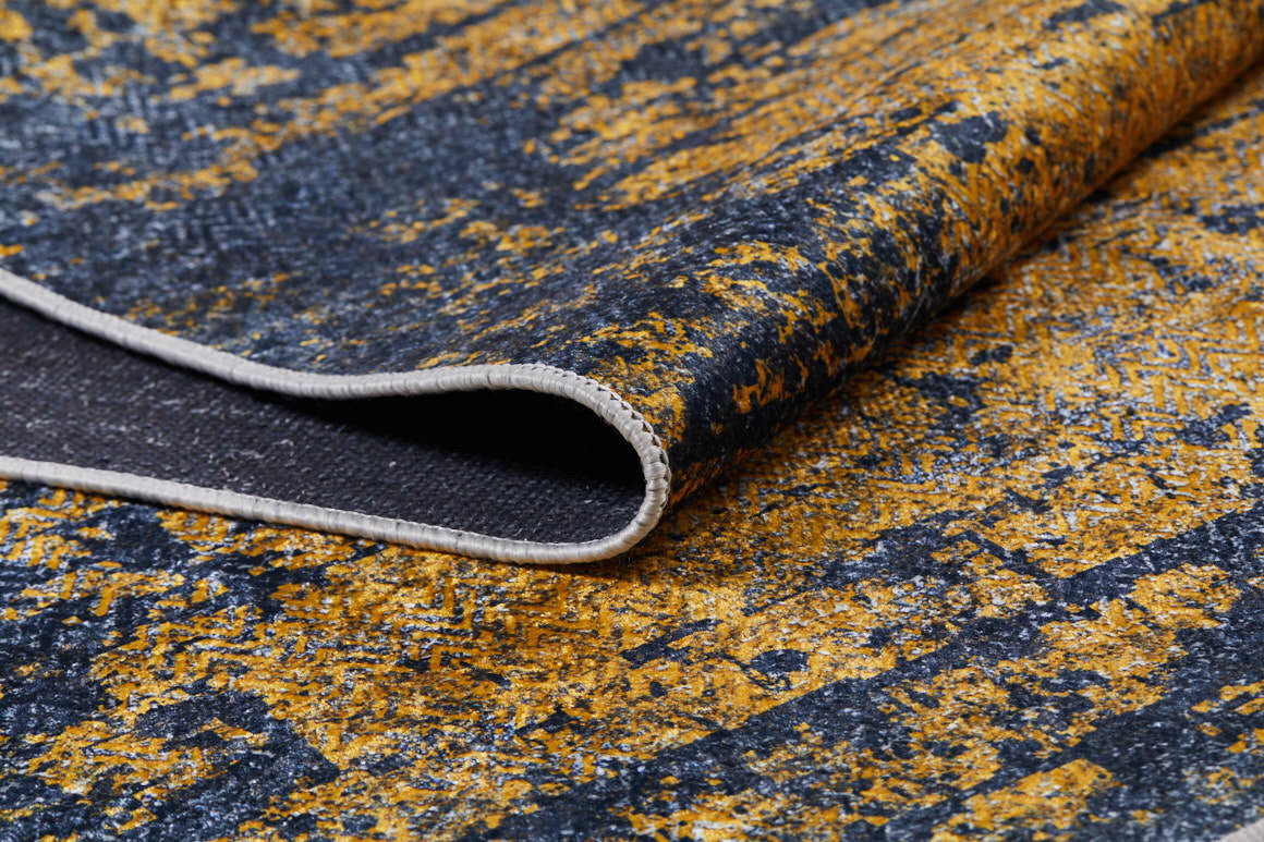 Close-up of Diagonal Dash - Washable Rug - JR1310: a modern yellow-gold rug featuring a textured abstract dark blue pattern with visible stitching and curled edge showing the underside—ideal for high-traffic areas.
