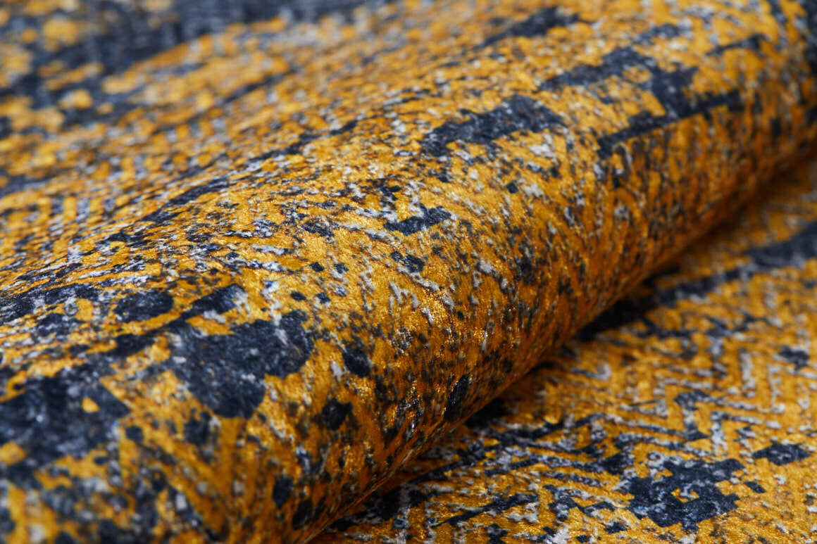 A close-up of the Diagonal Dash - Washable Rug - JR1310 shows its mottled yellow, black, and gray abstract geometric pattern. Soft with visible fibers and a slightly raised surface, it’s durable and perfect for high-traffic areas.