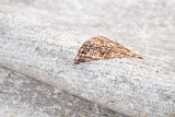 A close-up of the Ebony Ivory - Washable Rug (JR1994), rolled to reveal its beige surface with small brown and orange triangles—an ideal choice for allergy-sensitive households and busy, high-traffic areas.