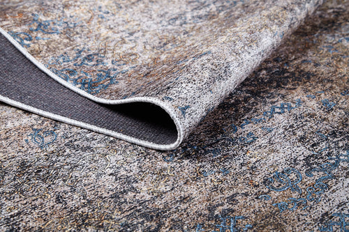 Load image 1 in gallery view. A close-up of the Elegant Leaf - Washable Rug - JR1945 in bronze, brown, beige, and blue shows its corner lifted to reveal texture and a washable underside—perfect for high-traffic areas.
