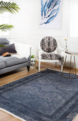 A modern living room with a gray sofa, patterned armchair, round side table, blue leaf wall art, and the Elegant and Modern - Washable Rug - JR1297—perfect for high-traffic areas. A decorative face vase sits near the sofa.