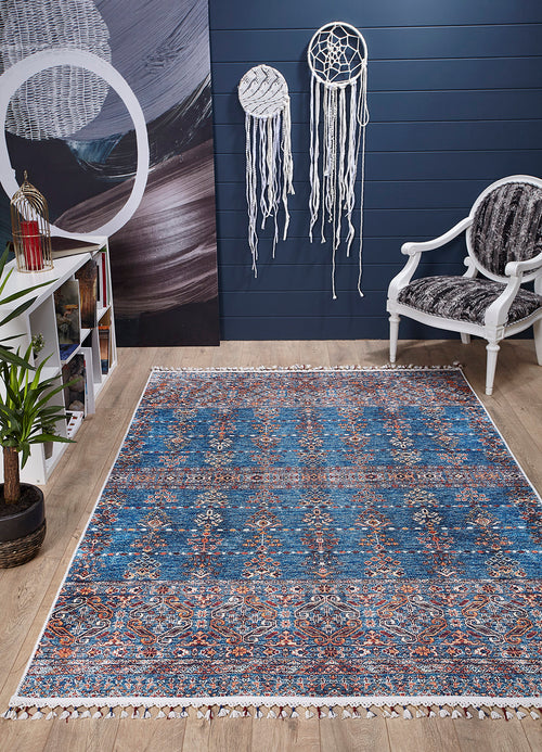 Load image 1 in gallery view. A cozy room with the Ethereal Essence - Washable Rug - JR5087 in blue, a white armchair with a patterned cushion, bookshelves, a green plant, two white dreamcatchers on a dark blue wall, and light wood flooring.