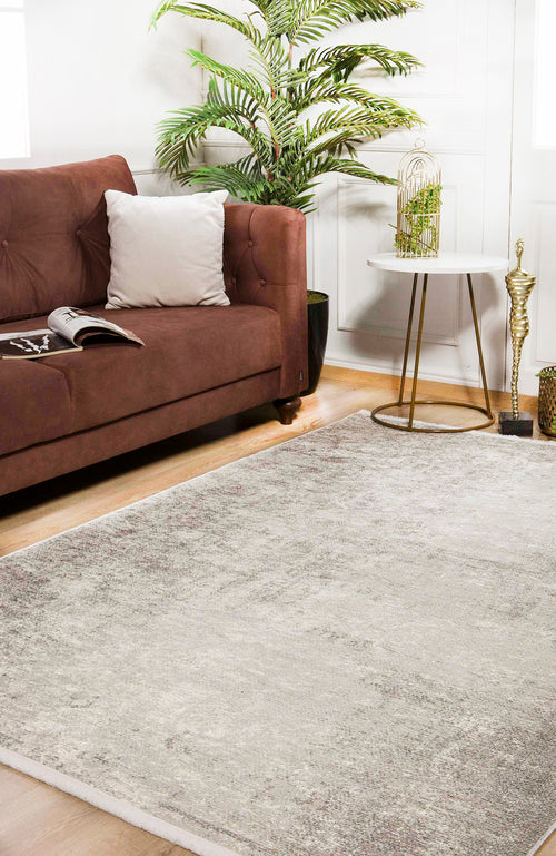 Load image 1 in gallery view. A modern living room featuring a brown sofa, white pillow, open magazine, Forest Canopy - Washable Rug - JR800, round white side table, decorative accents, potted plant, and bright natural light streaming through windows.