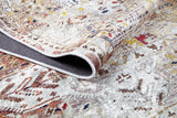 A close-up of the Global Getaway - Washable Rug - JR1667 displays its muted beige, brown, red, and blue pattern, ideal for high-traffic areas; the edge is slightly folded to reveal the underside.