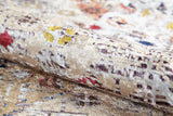 A close-up of the Global Getaway - Washable Rug - JR1667 in cream and beige, featuring a soft velvety texture with abstract red, yellow, brown, and blue accents. Partially rolled to reveal its sheen and detailed design—ideal for high-traffic areas.
