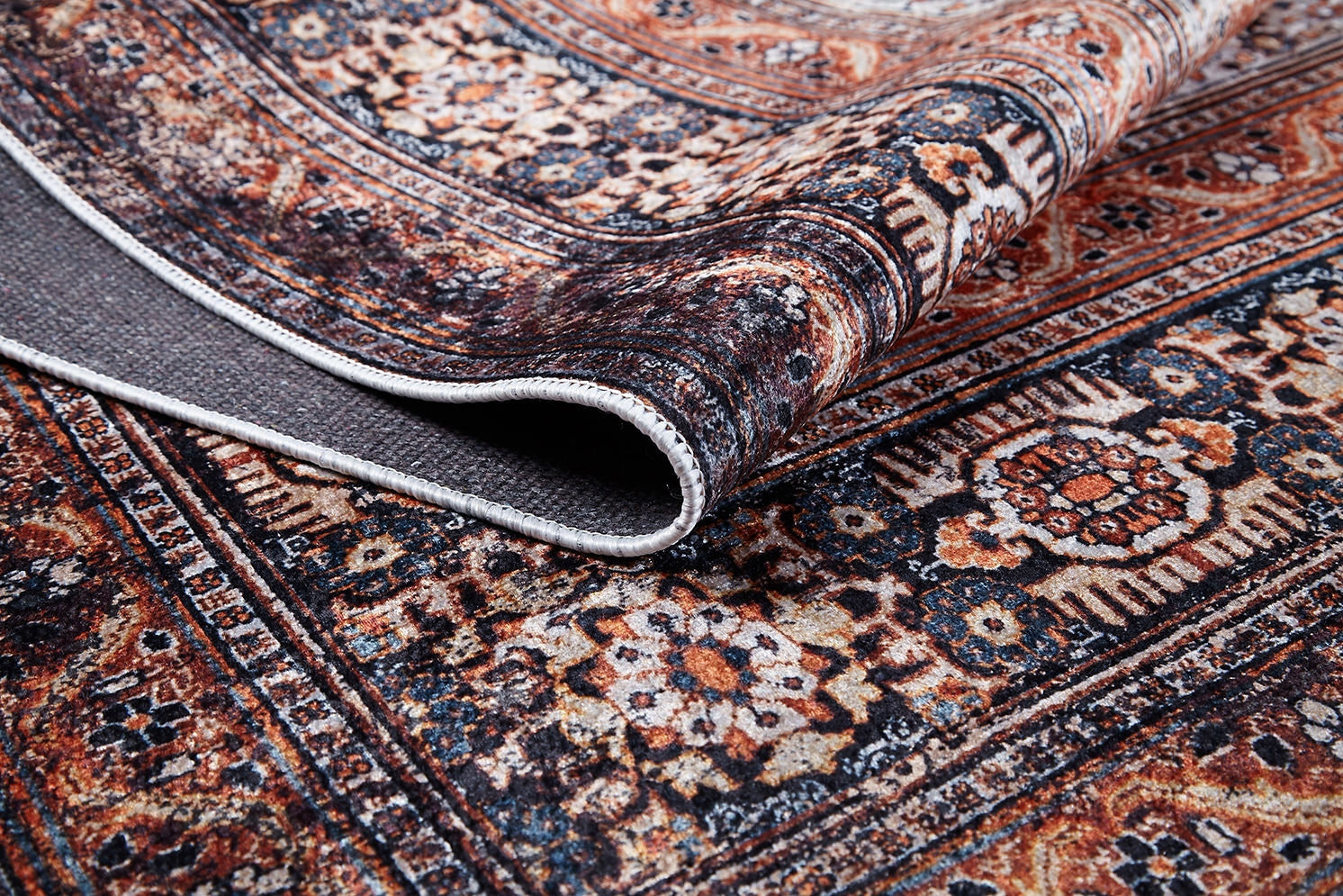 A close-up of the Golden Legacy - Washable Rug (JR1931) showcases its intricate floral and geometric designs, with the edge curled to reveal texture and thickness—ideal for high-traffic areas.