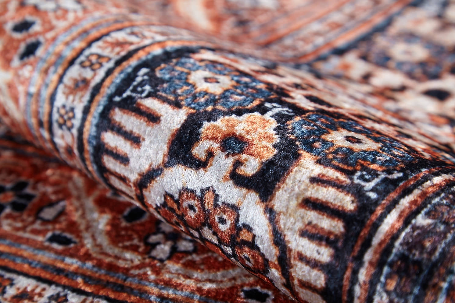 A close-up of the Golden Legacy - Washable Rug - JR1931, showcasing intricate floral and geometric patterns in brown, cream, black, and blue on a curved surface—perfect for high-traffic areas.