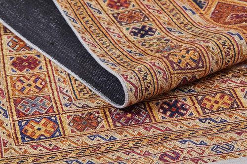 Bild 1 in Galerieansicht laden. A close-up of the Grandiose Grace - Washable Rug - JR44 shows its multicolored geometric patterns in red, gold, blue, and brown. A folded corner reveals the dark underside—ideal for high-traffic areas.