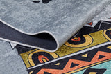 A close-up of the Groovy Bear - Machine-Washable Rug JRC093 in gray-anthracite shows a folded edge and bold geometric shapes in yellow, orange, black, and teal—ideal for adding style to high-traffic areas.