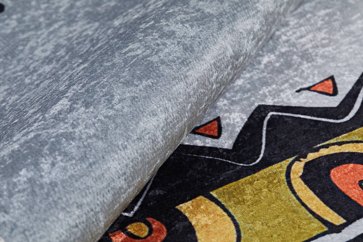 Close-up of the Groovy Bear - Machine-Washable Rug JRC093 in textured gray-anthracite, featuring black, yellow, and orange geometric patterns. Its thick edge is slightly lifted—ideal for high-traffic areas.
