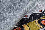 Close-up of the Groovy Bear - Machine-Washable Rug JRC093 in textured gray-anthracite, featuring black, yellow, and orange geometric patterns. Its thick edge is slightly lifted—ideal for high-traffic areas.