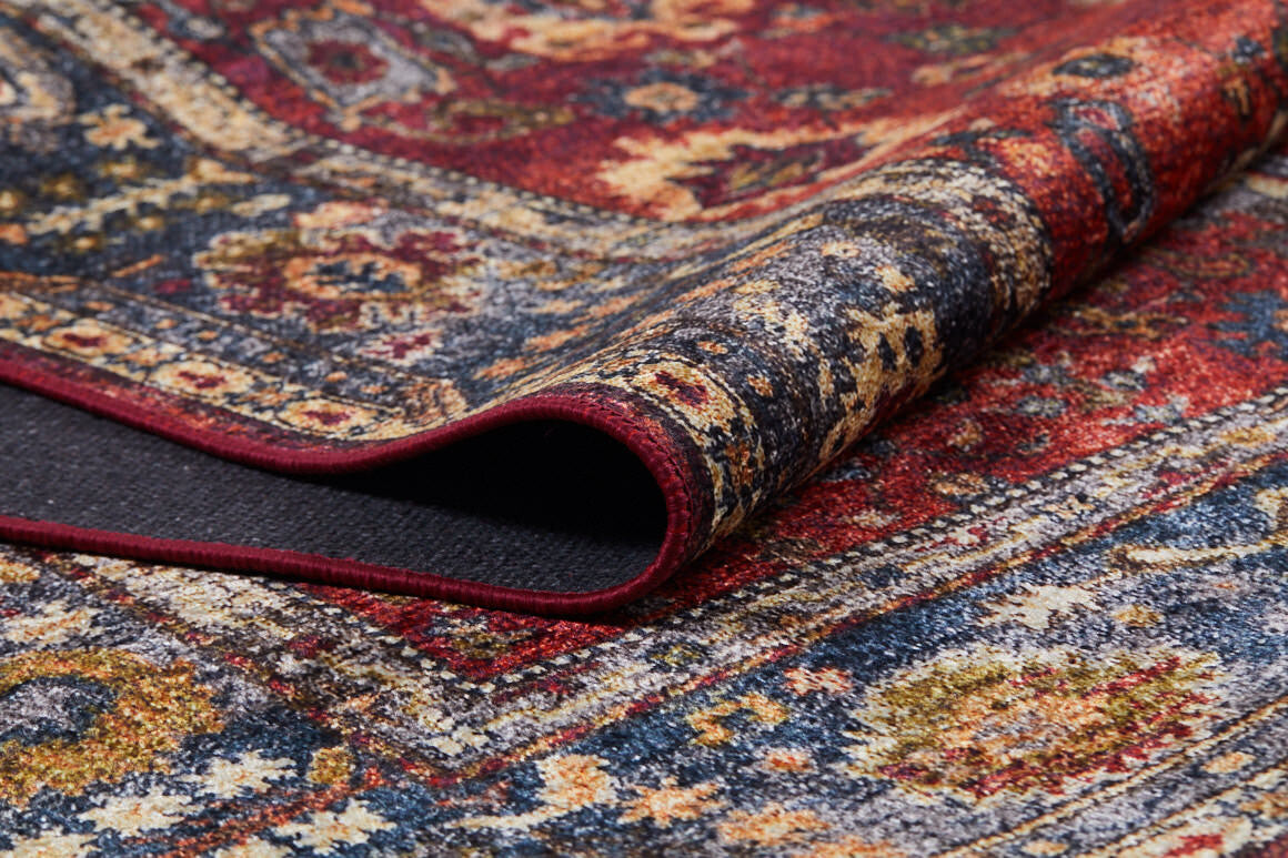 A close-up of the Historic Hues - Washable Rug - JR898 (Outlet) US, folded to display intricate blue, yellow, and cream floral and geometric patterns—making it a stylish, durable choice for high-traffic areas.
