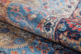A close-up of the Imperial Weave - Washable Rug - JR1969, rolled to showcase its vintage Persian-inspired blue design with intricate floral patterns in shades of blue, red, cream, and gold—durable for high-traffic areas.