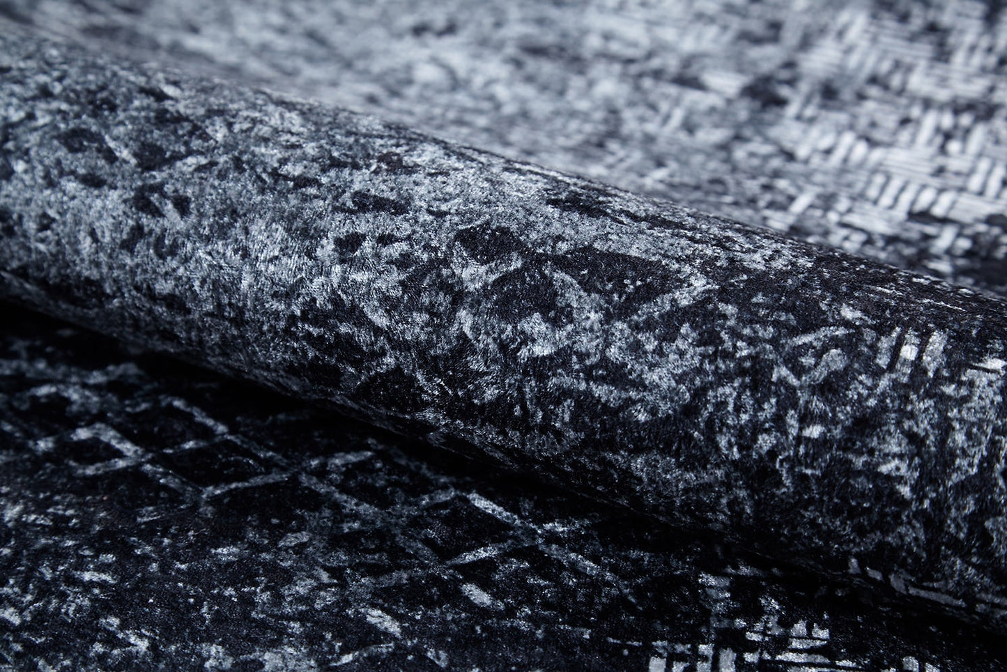 Close-up of the Infinity Garden - Washable Rug - JR1749: a rolled gray-anthracite rug with an abstract black and gray geometric pattern—stylish, washable, and perfect for high-traffic areas.