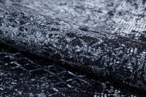 Load image 1 in gallery view. Close-up of the Infinity Garden - Washable Rug - JR1749: a rolled gray-anthracite rug with an abstract black and gray geometric pattern—stylish, washable, and perfect for high-traffic areas.
