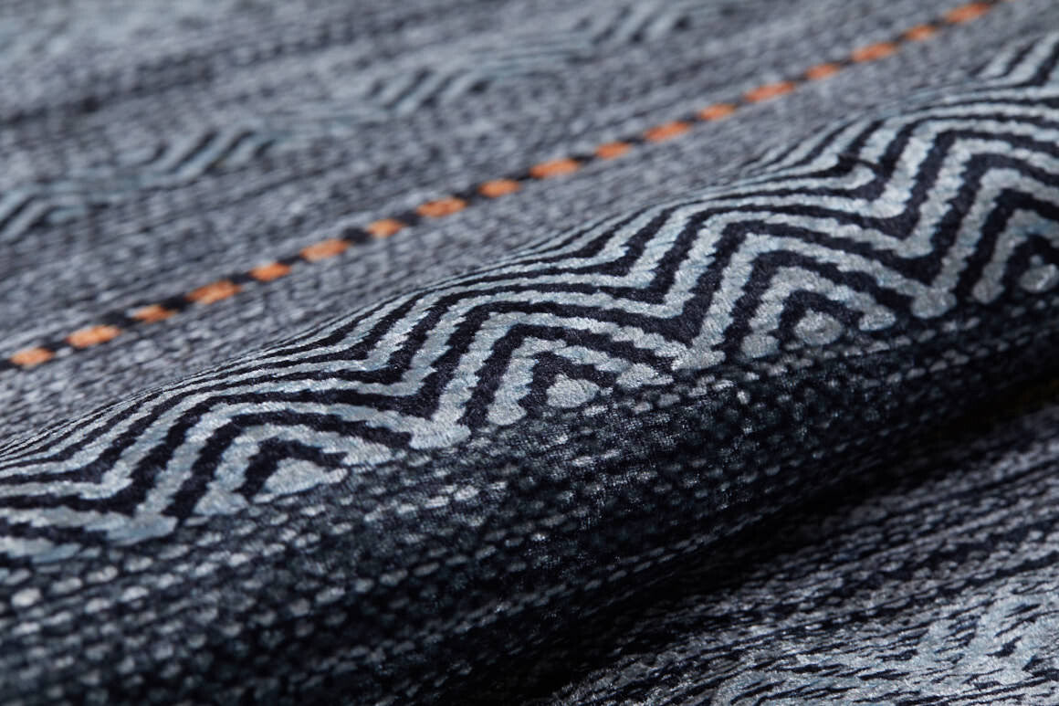 Close-up of the Metro Lines - Washable Rug - JR1548 in gray-anthracite, featuring a blue and gray geometric zigzag pattern with a line of small orange dots. Its soft, slightly raised texture is perfect for high-traffic areas.